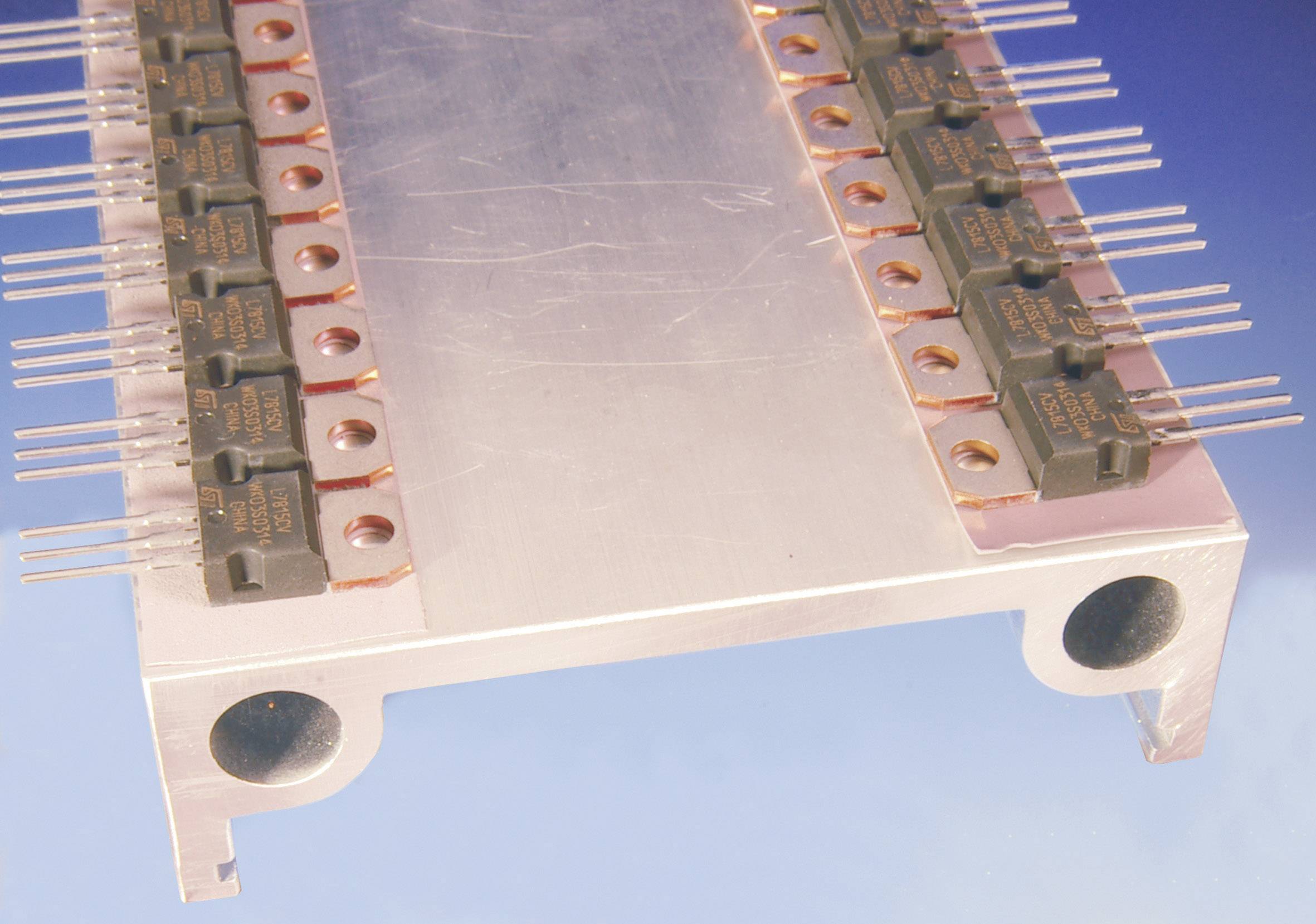 A metal strip with several small, evenly arranged electrical components and protruding pins used for electronics.