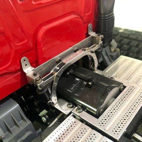 Close-up of a red rear axle of a model vehicle, with visible engine and metal mount. Tyres are partially visible.