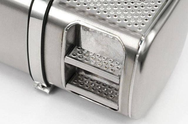 A close-up of a silver garlic press with two holes for juice extraction.