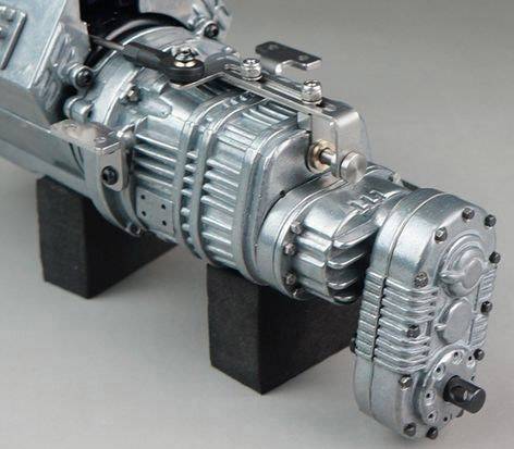 A silver machine gearbox with multiple gears and screws, mounted on black blocks.