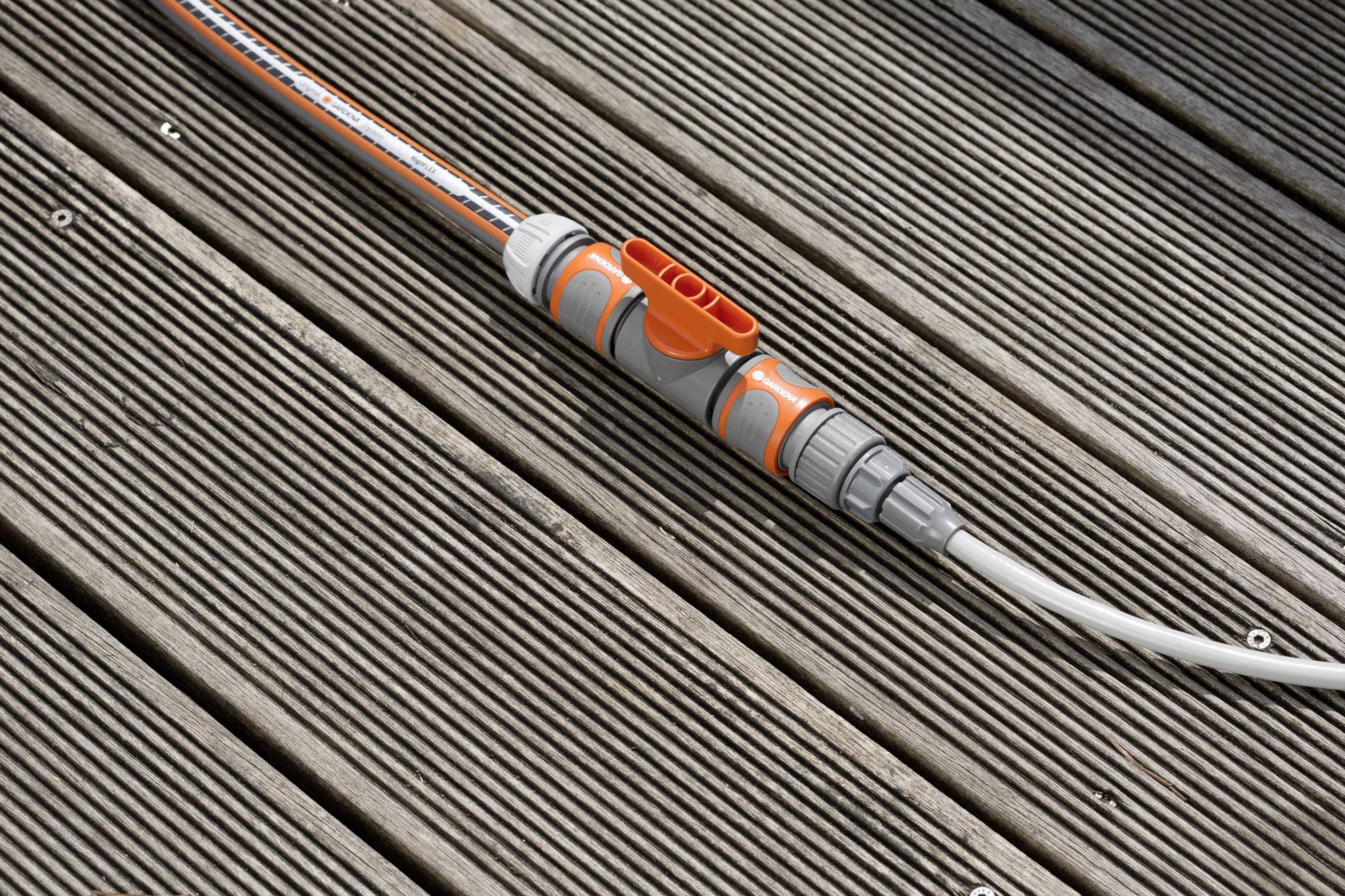 A grey hose with orange connectors is lying on a wooden deck.