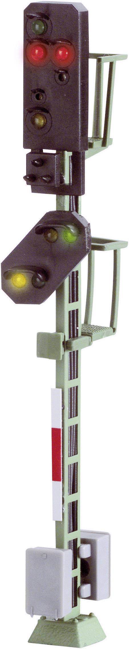 A model railway signal shows two red and one yellow light. It is vertically positioned with a green mast. Signal indicates 'Stop'.