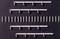 White plastic clips and wall plugs evenly arranged on a black background, many in a row, others in groups.