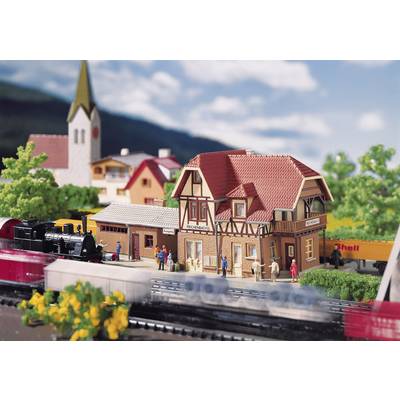 A miniature model of a German village with a half-timbered house, train and church in the background. People are standing in front of the house.