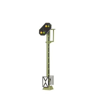 A green and yellow light signal on a tall mast indicates a level crossing. It is situated in a rectangular metal frame.