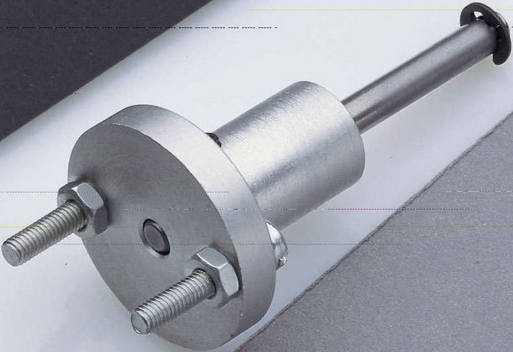 Metal bolt with a round base plate and two nuts, lying on a grey and white surface. Used for fastenings.