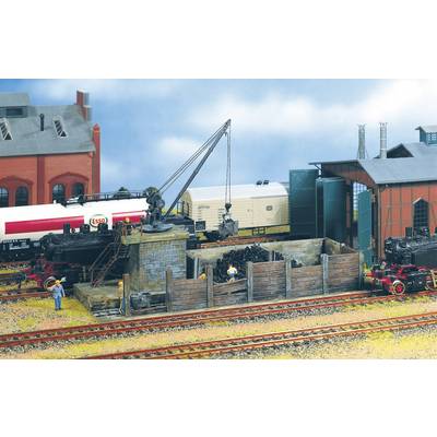 A model railway scene depicts a goods yard with steam locomotives, a coal bunker, and a loading station. A crane stands ready.