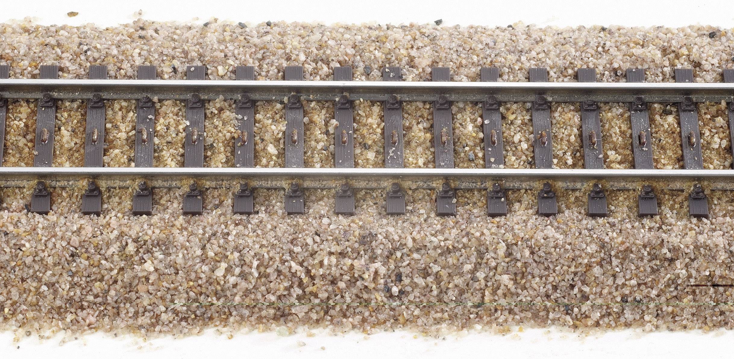 A miniature railway track on a gravel-covered surface.
