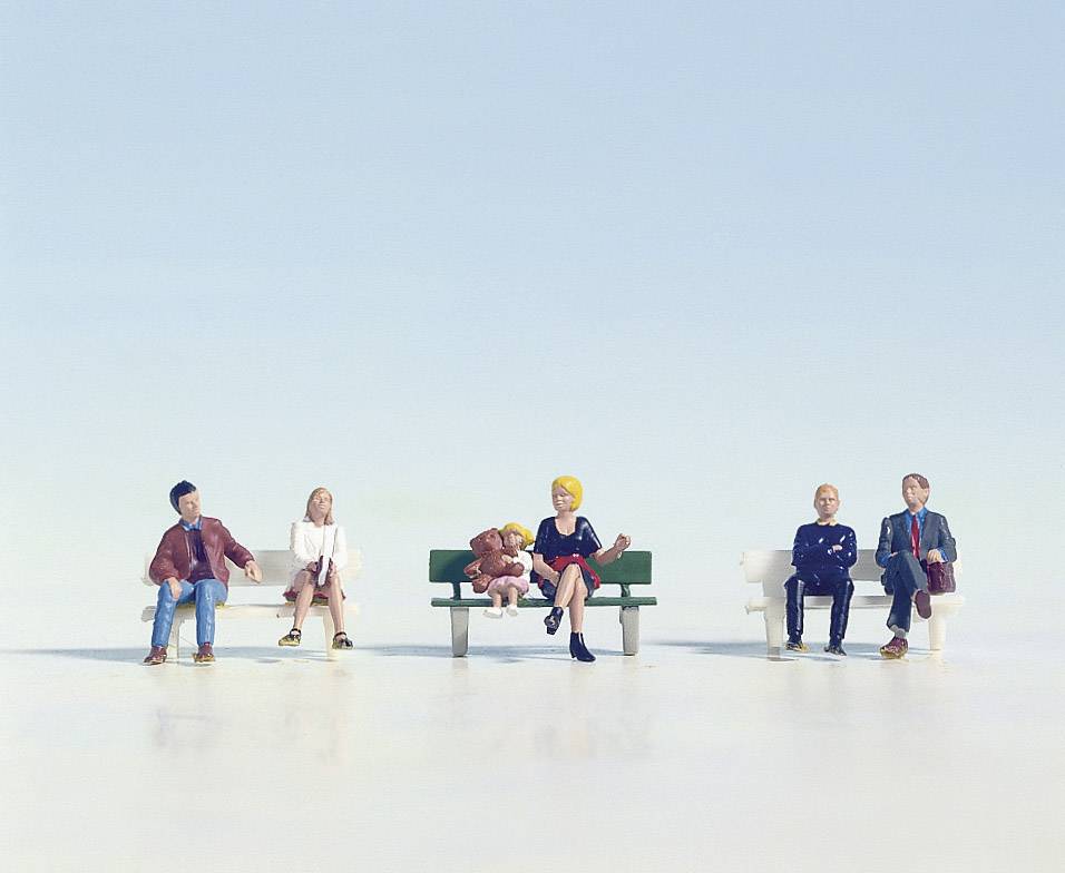 Miniature figures sit on benches spaced apart from one another, symbolising social distancing. A bright sky is in the background.
