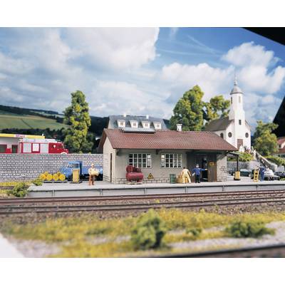 A miniature railway landscape with tracks in the foreground. In the background, a small building and a church, surrounded by trees.