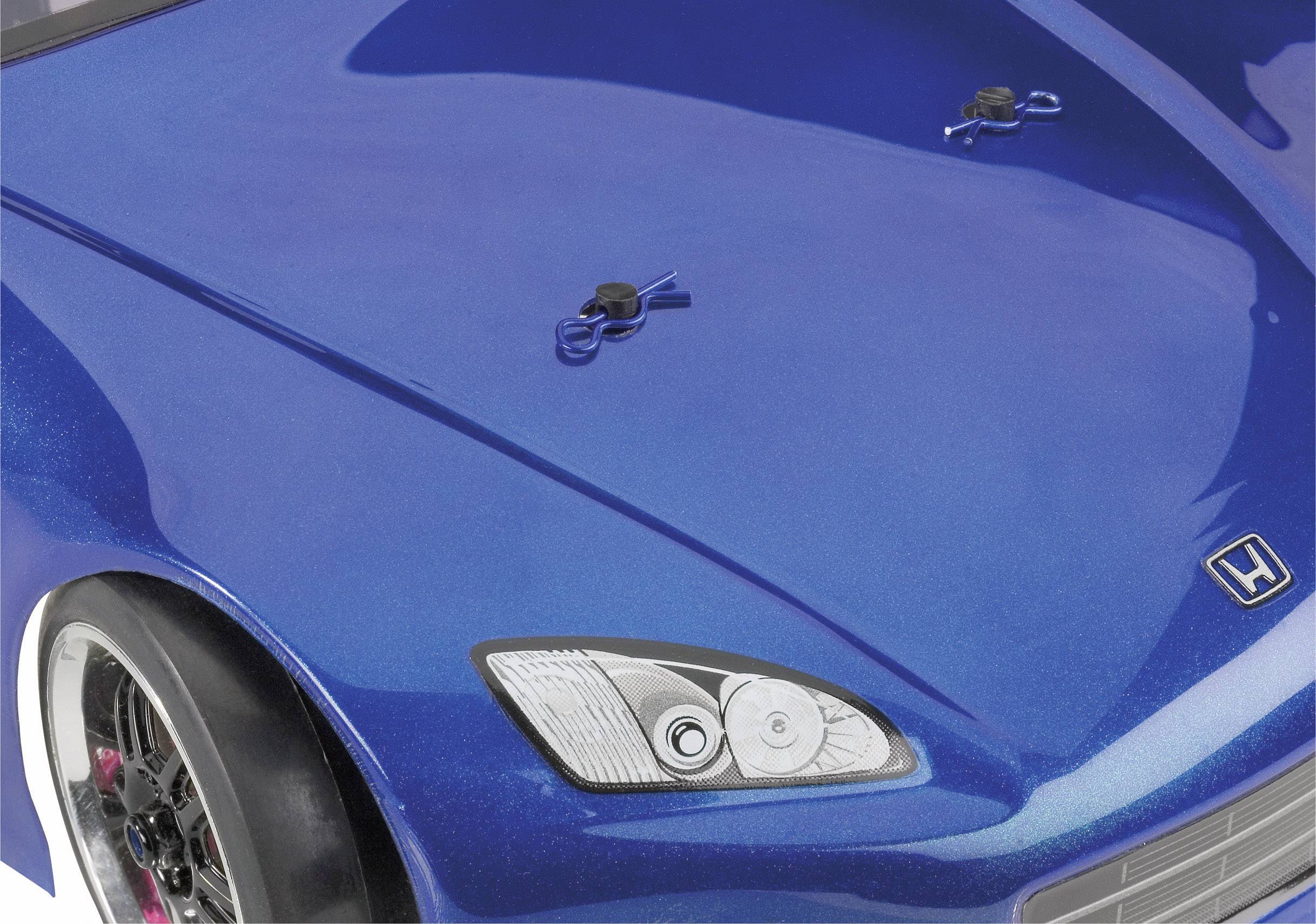 Close-up of a blue sports car, with part of the bonnet visible in the image. Two bonnet catches and a chrome headlight are visible.