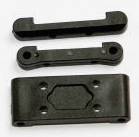 Three black metal components with openings and notches are lying side by side. They appear to be part of a mechanical or technical system.