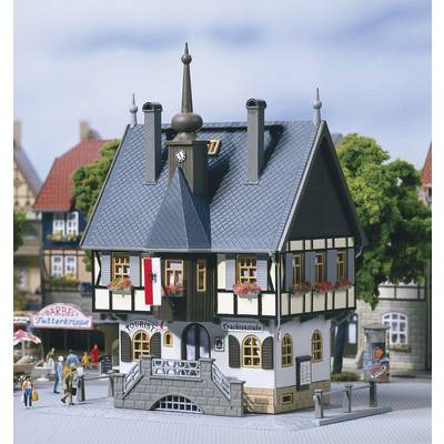 A miniature model of a half-timbered house with a stepped entrance and a small turret. A sign reading 'Tourist' hangs above the door.