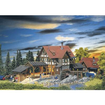 A miniature model depicts a traditional half-timbered house with a red roof in a rural setting with trees and flowing water.