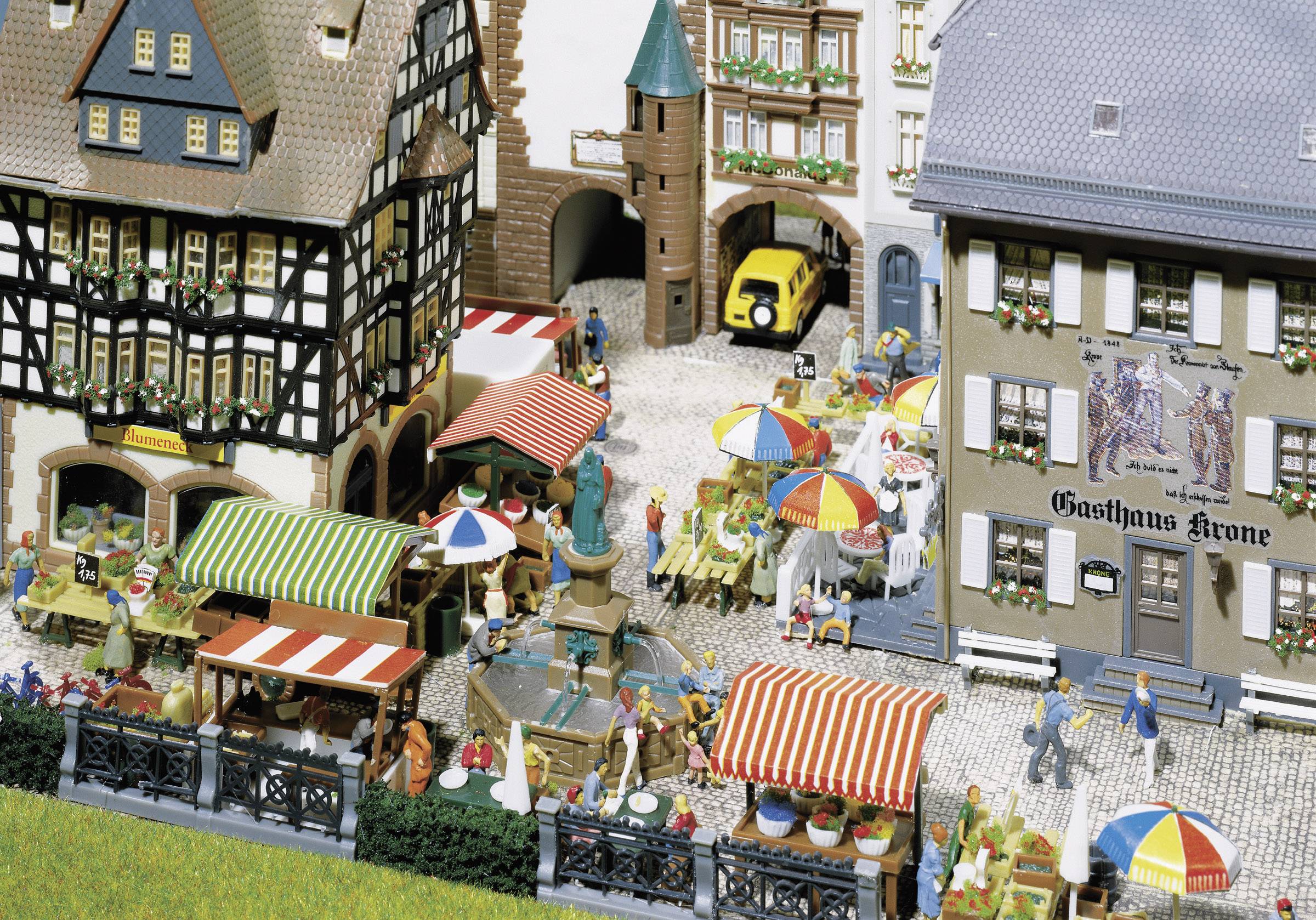 A bustling street scene in an old town, with half-timbered houses, cafés with colourful parasols, and people strolling leisurely.