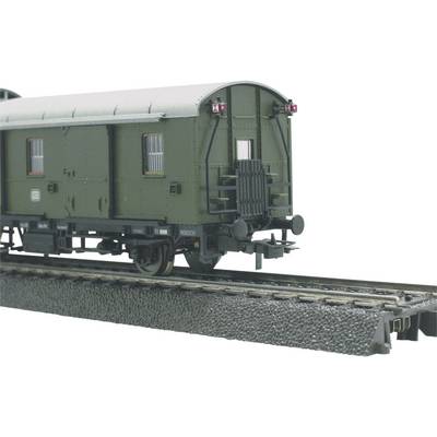 Toy train on a model railway track, green carriage with black wheels and red tail lights, surrounded by intricate detailing.