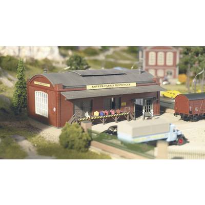 A model of a factory with the inscription 'Mopsinger Suitcase Factory', surrounded by trees, a lorry, and a goods wagon.