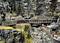 A detailed model railway layout shows trains crossing bridges and passing through tunnels in a rocky, wooded landscape.