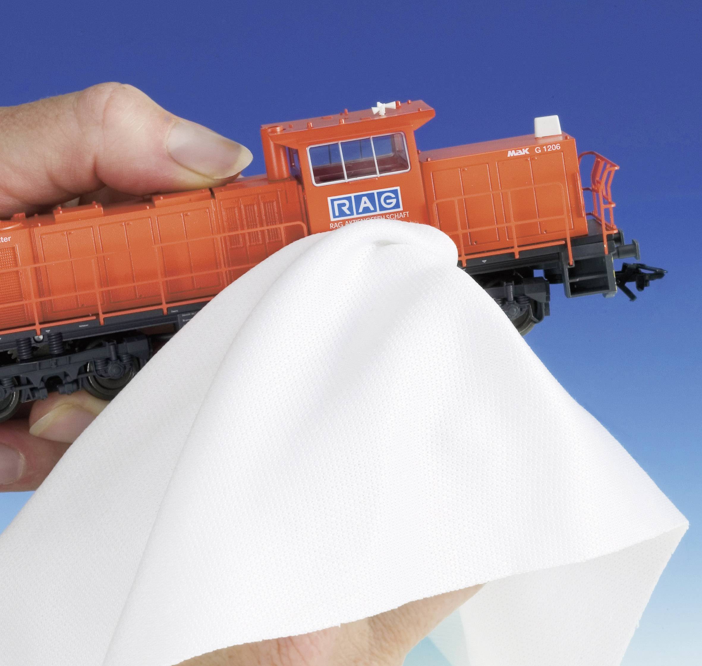 A person is wiping a orange model locomotive with a cloth. The locomotive has the 'RAG' logo on its side.
