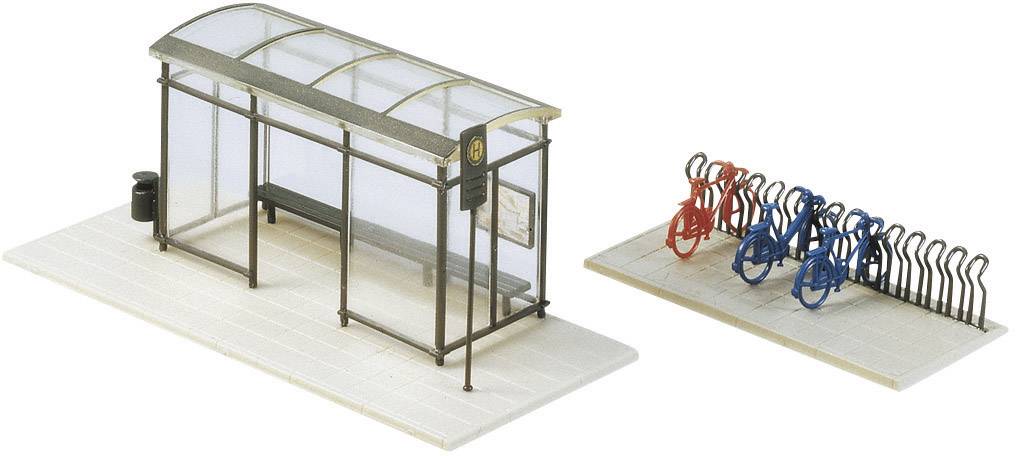Bus stop in model scale with roof, bench and litter bin. Next to it, a bicycle rack with several bicycles.