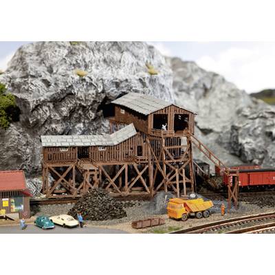 A miniature diorama scene depicts a mine with wooden structures, small vehicles, and tracks set against a rocky backdrop.