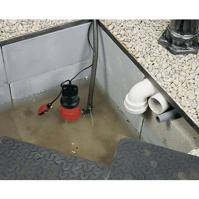 Pump in a water-filled basement. White pipes along a wall, pebble stones as floor covering.