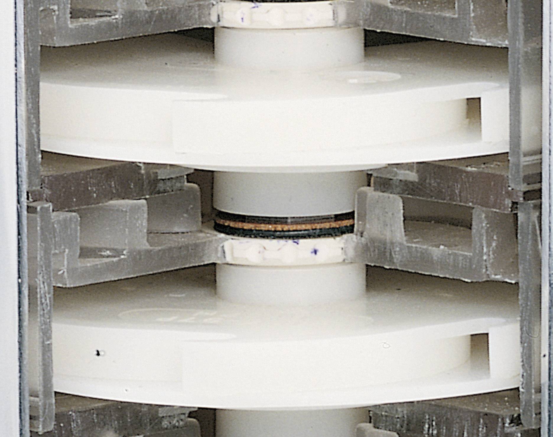 A stack of cooling towers, each with two white blades connected by a central axis.