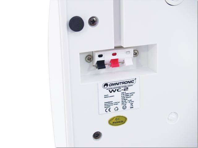 Back of a speaker with cable connections and nameplate.