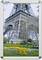 The Eiffel Tower towers over a park with flowers and bare trees. Several people are visible below, observing the landmark.