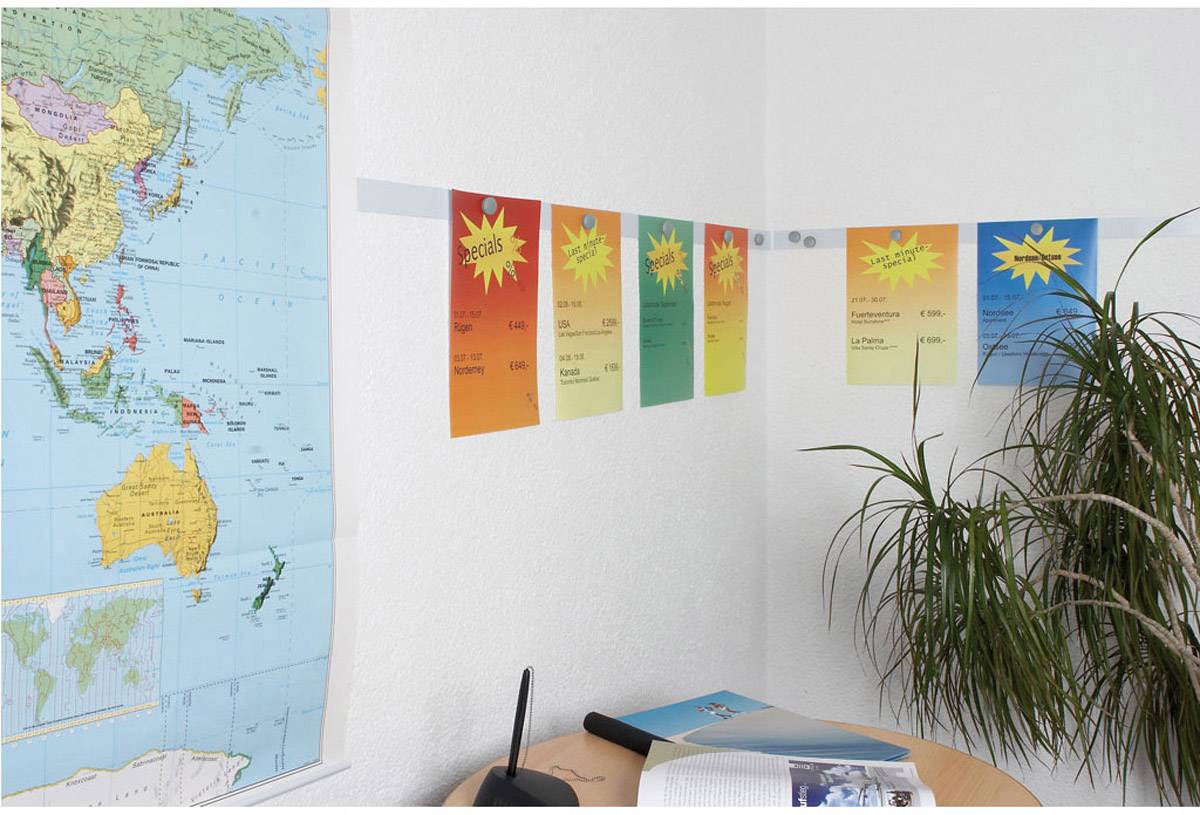 Wall with colourful posters in an office; next to a world map on a desk with books and a plant.