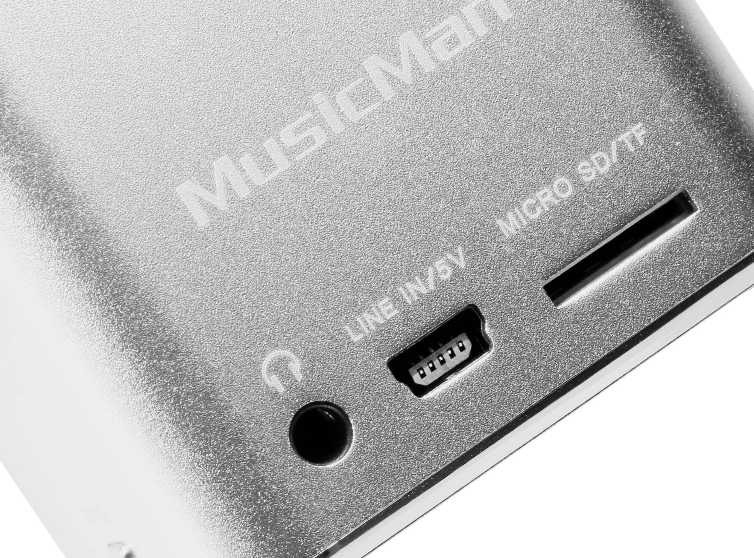 A silver electronic device with connections and the inscription 'MusicMan'. A headphone socket, micro-USB, and micro-SD card slot are visible.
