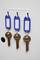 Three keys hang side by side on blue key rings from white hooks.