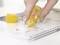 A hand uses a yellow Tesa correction roller to amend handwritten notes in a notebook.