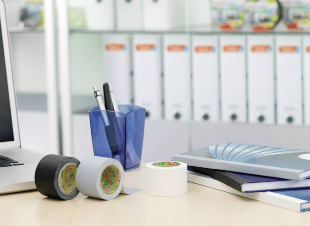 Laptop, pencil holder, sticky tape, and notebooks on a desk in front of a filing cabinet. Office environment showing work materials.