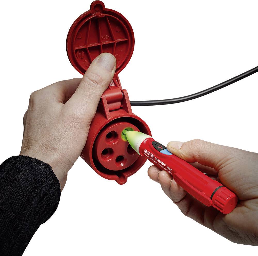 A person is testing a red socket with a voltage tester to check electrical safety.