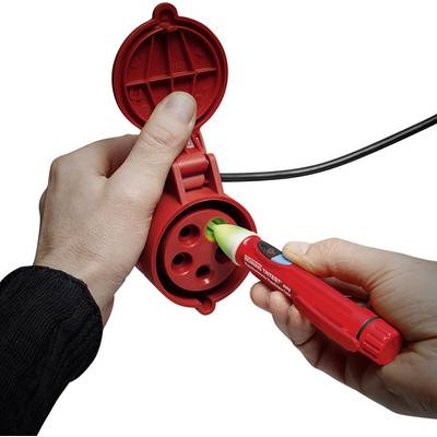 A person is testing a red socket with a voltage tester to check electrical safety.
