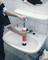 A person is using a red plunger to unblock a sink in a tiled bathroom.