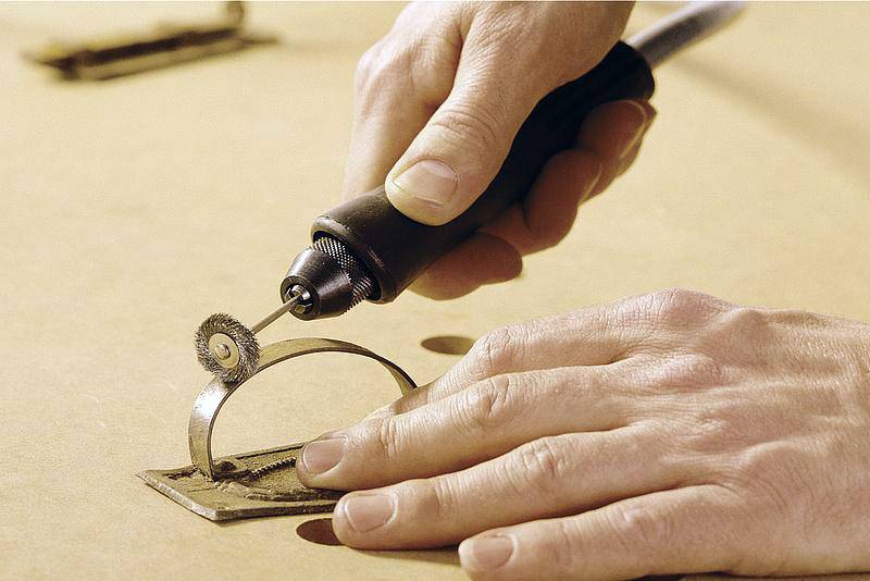 A person is using a hand tool to work with metal. The tool is cutting a circular cut-out into a metal plate.