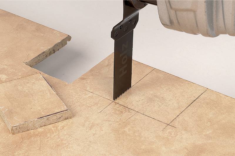 A reciprocating saw precisely cuts a rectangular hole in a wooden board. Markings on the board indicate the cutting path.