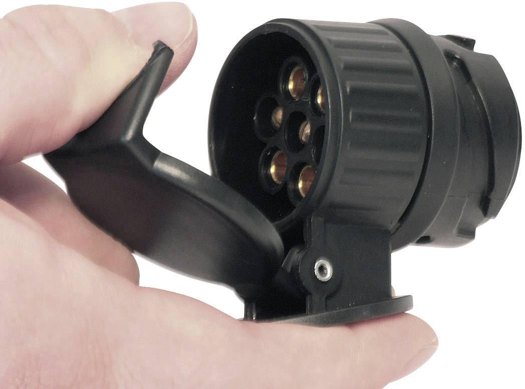 A hand is holding a round, black pendant plug with an open lid, pointing to the internal contacts.