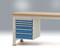 Desk with blue drawer unit on the left, light wooden worktop; suitable for office or workshop.