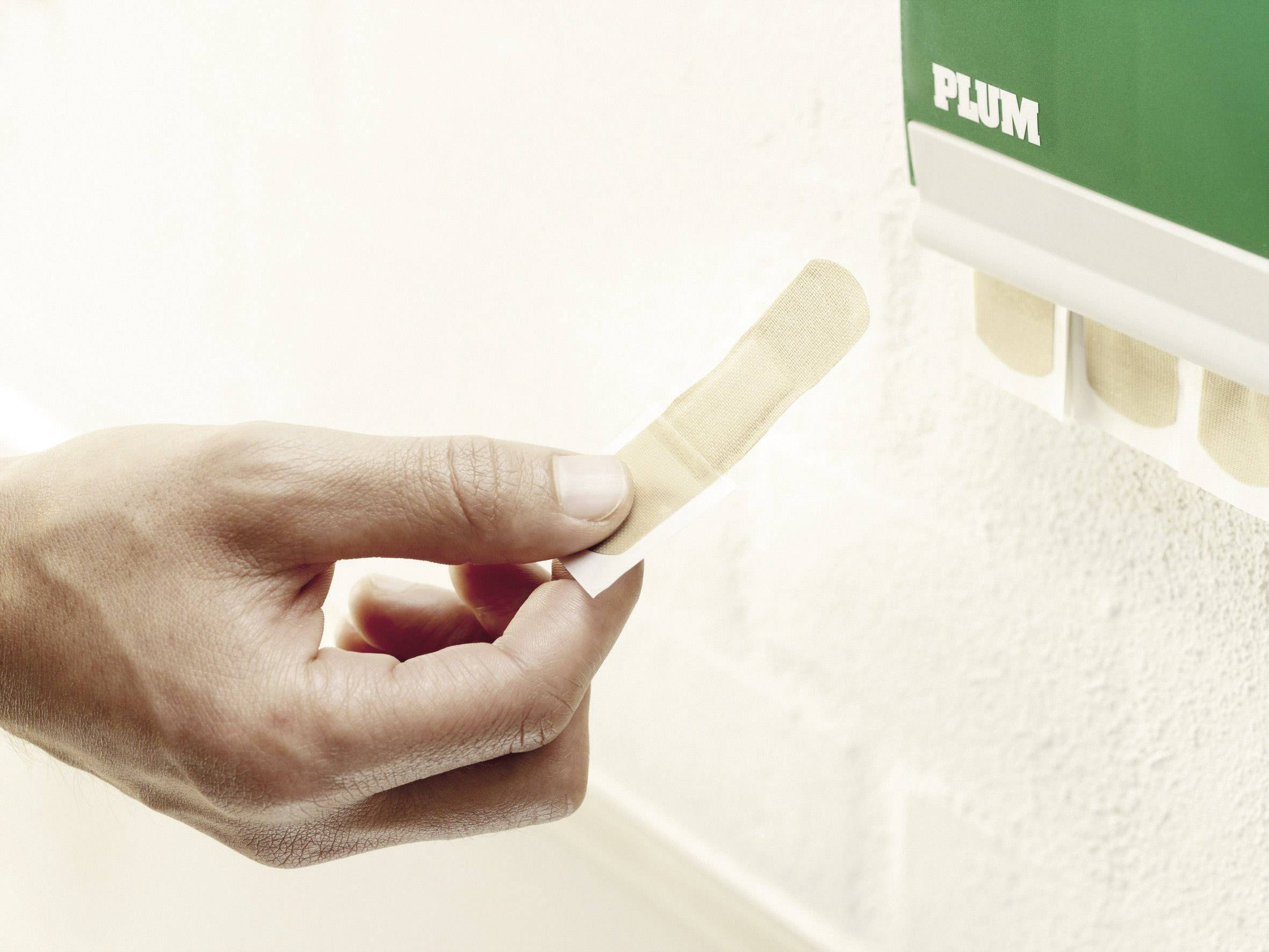 A hand takes a plaster from a green first aid dispenser on a white wall.
