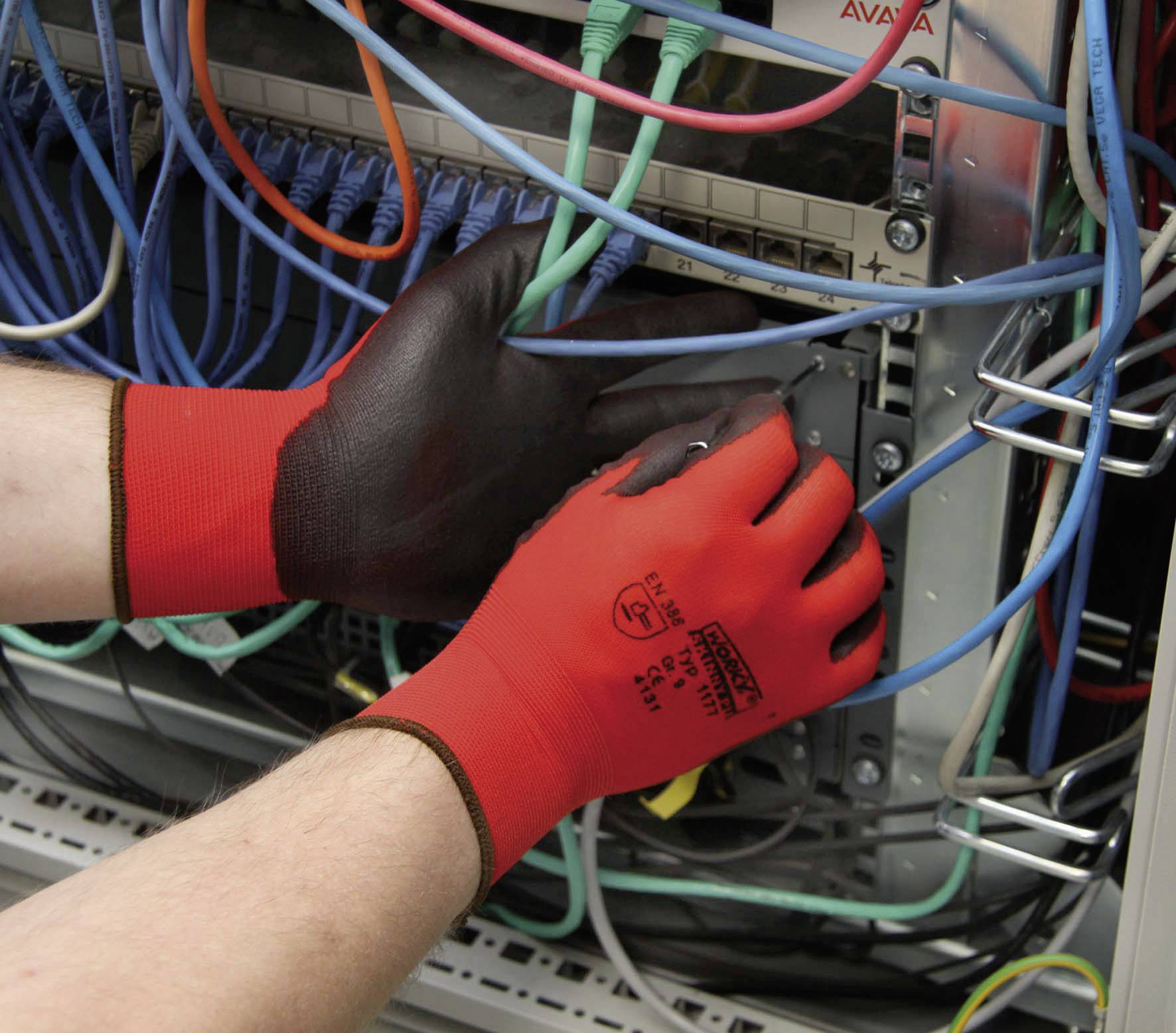 A person wearing red and black work gloves is plugging cables into a server cabinet.
