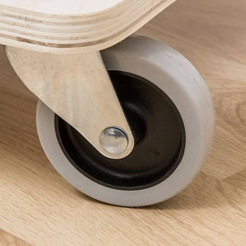 Close-up of a grey castor wheel with a metal mounting on a wooden floor. Focus on the texture and material combination.