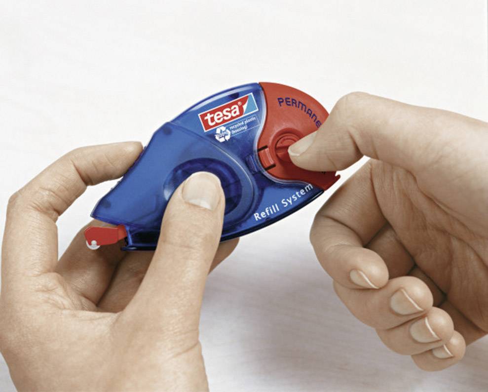 Two hands are holding a tesa correction roller. One hand is pulling out the tape while the other stabilises the roller.