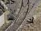 A railway model shows tracks with a points lever on the right and a wooden barrier on the left. There are grassy patches along the ballast beds.
