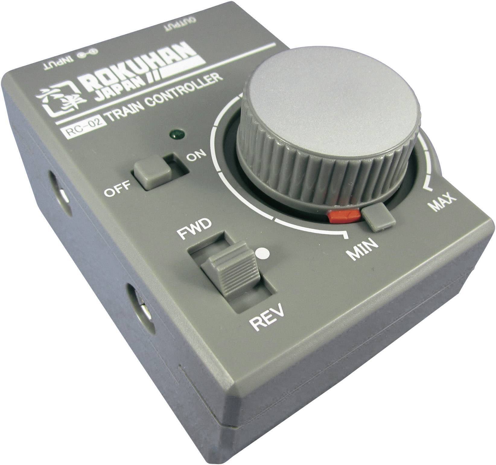 Grey model railway controller with a large rotary knob for speed control. Buttons for forward and reverse travel, and an on/off switch.