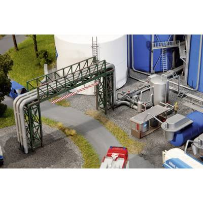 Industrial site with pipes, tanks and control centre. A worker stands in a control area. Trees and vehicles in the background.