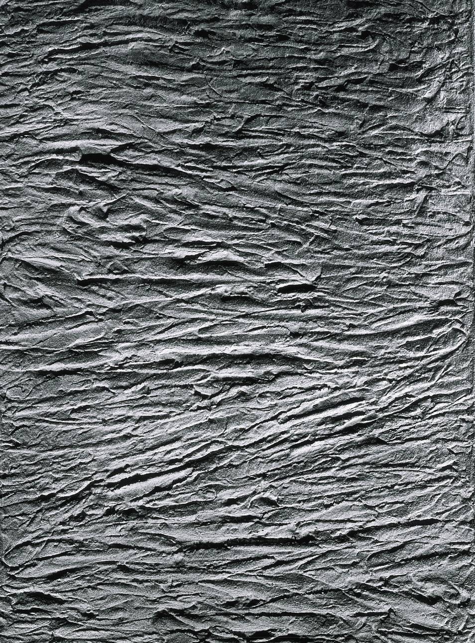 A grey, textured wall surface with irregular grooves and folds reminiscent of crumpled paper.