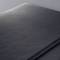 A close-up of a matte black laptop surface with fine lines that impart a smooth and elegant texture.
